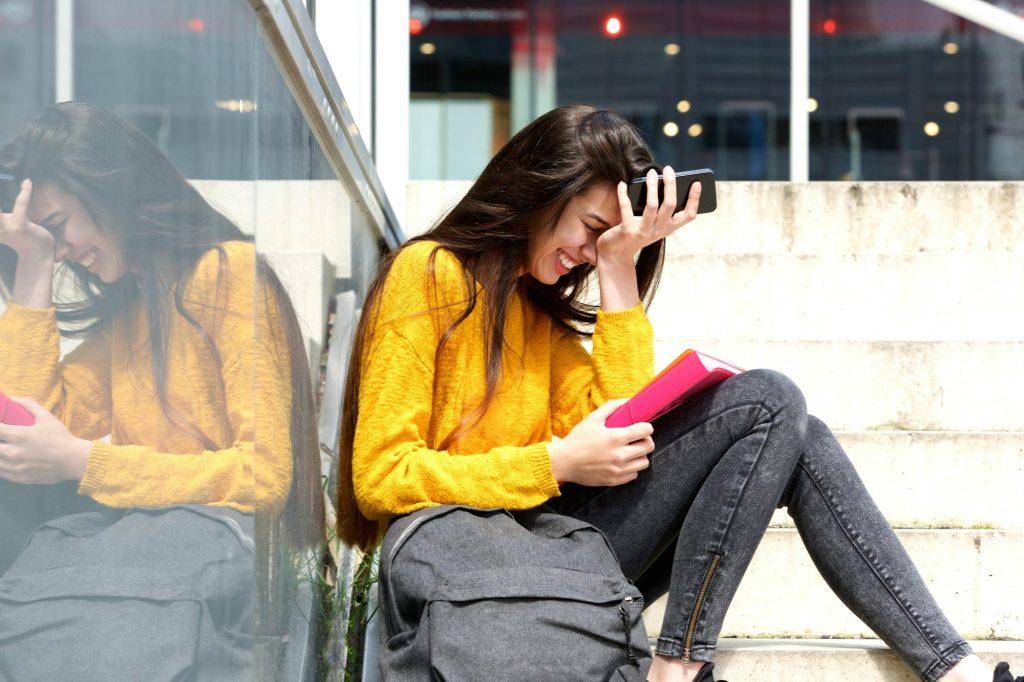 Young woman laughing with bad and mobile phone